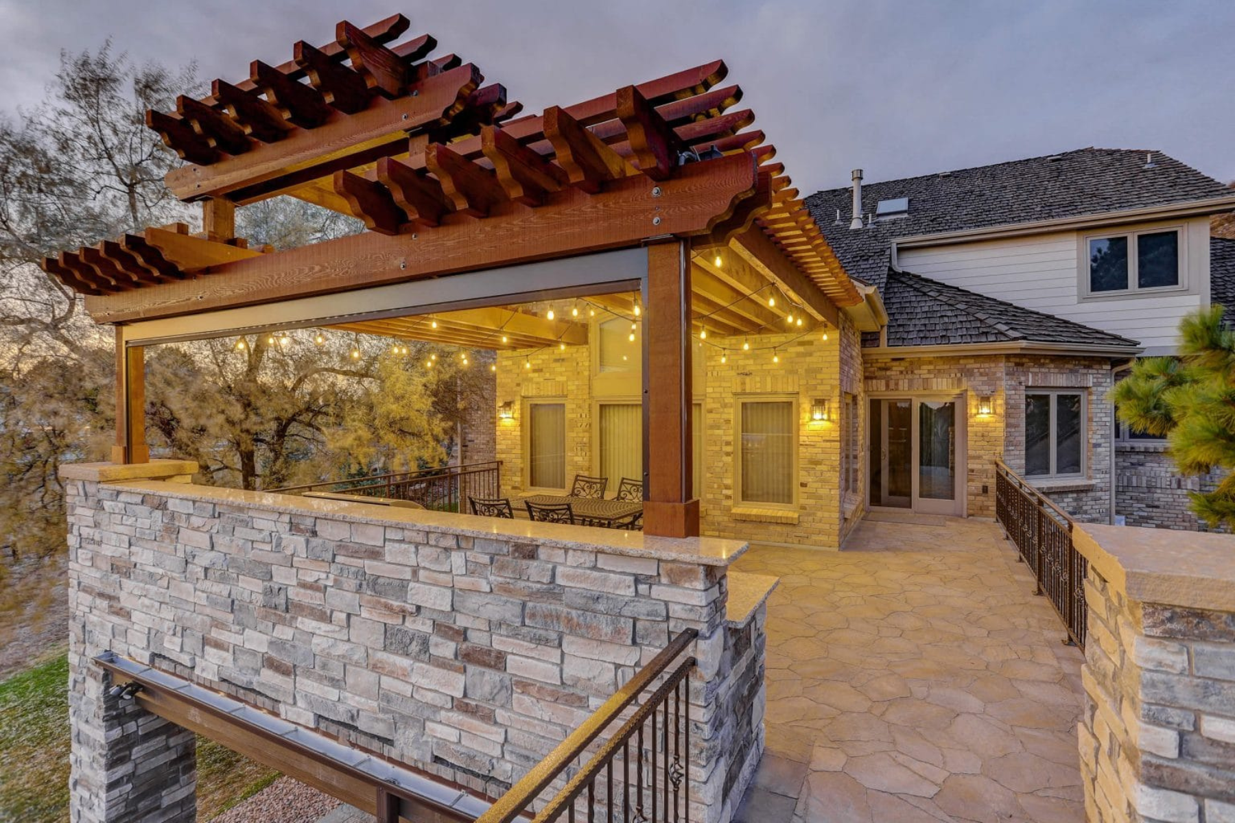 A patio with an outdoor pergola and stone wall.